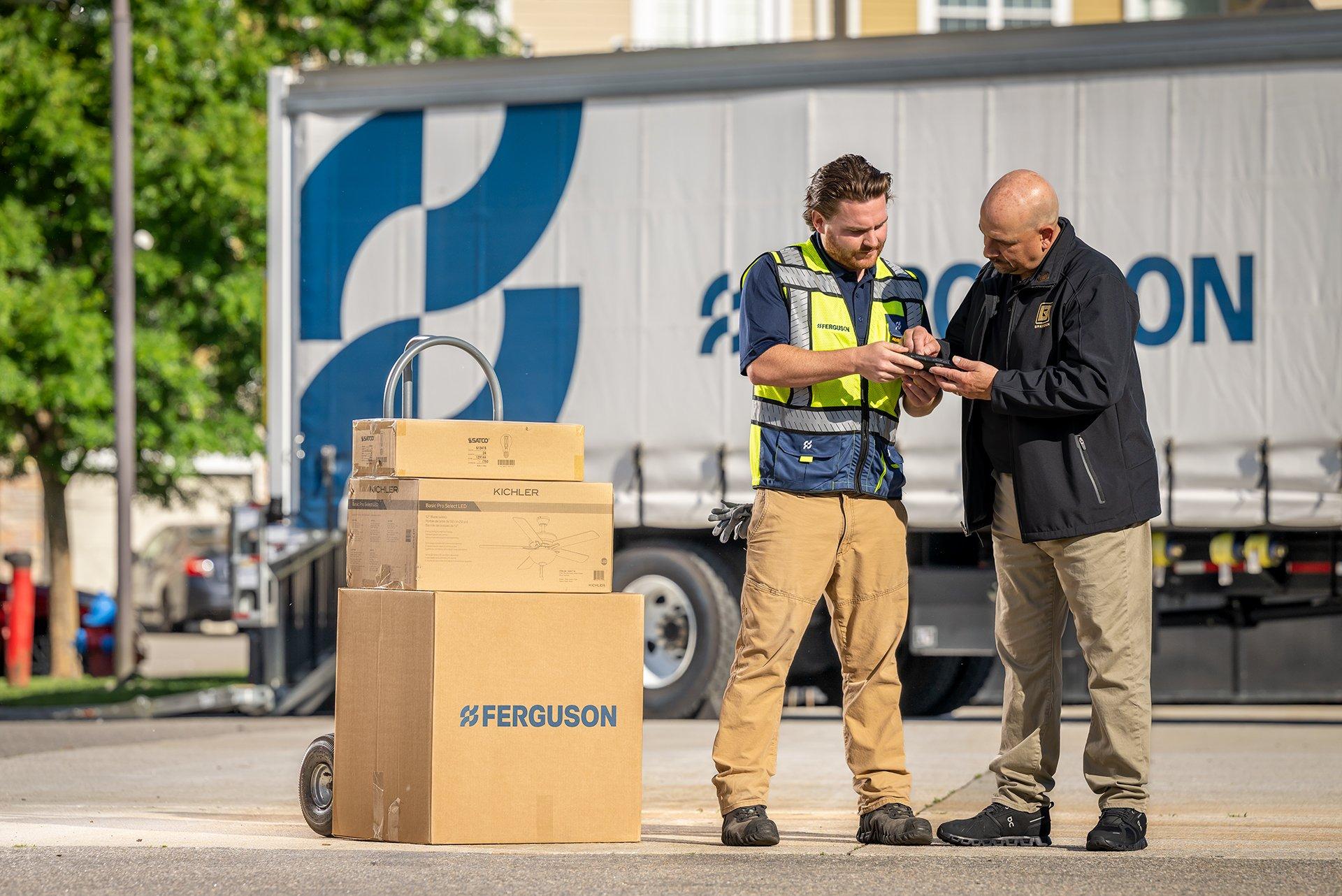 A customer signs a tablet from a Ferguson associate delivering packages on a dolly, and a Ferguson truck is in the background.