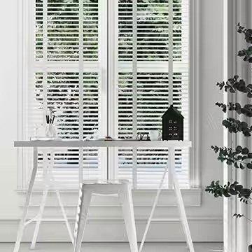 View of open 2-inch white faux wood blinds from inside a brightly lit living room.
