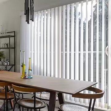 View of slightly open 3.5-inch white vertical blinds on a sliding glass door in an elegant dining room.