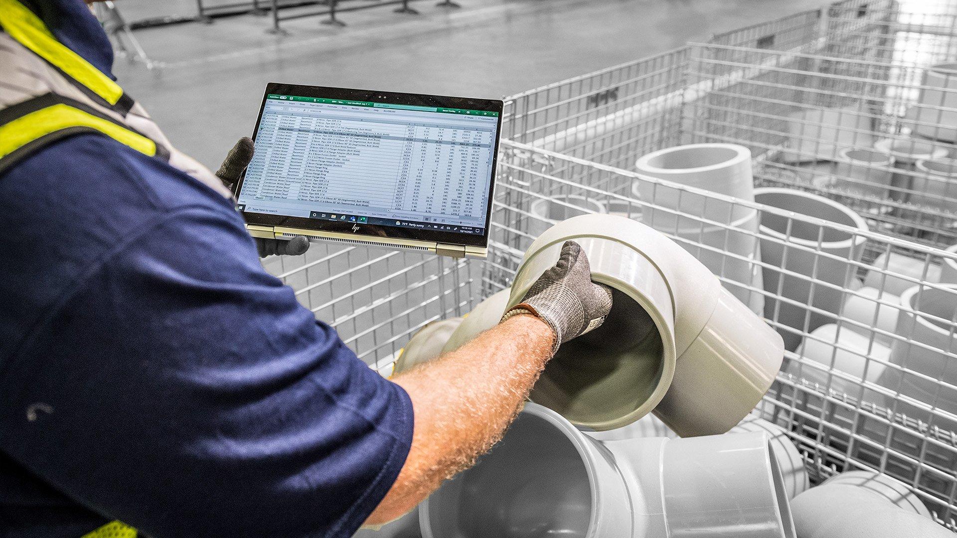 Associate holds tubing with laptop open for inventory ordering. 