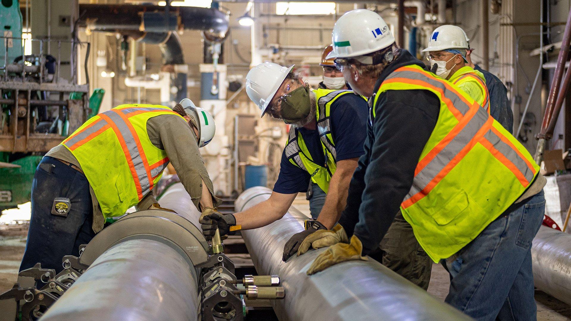 Two Ferguson Industrial associates instruct about types of pipe material for different purposes in a conference room.