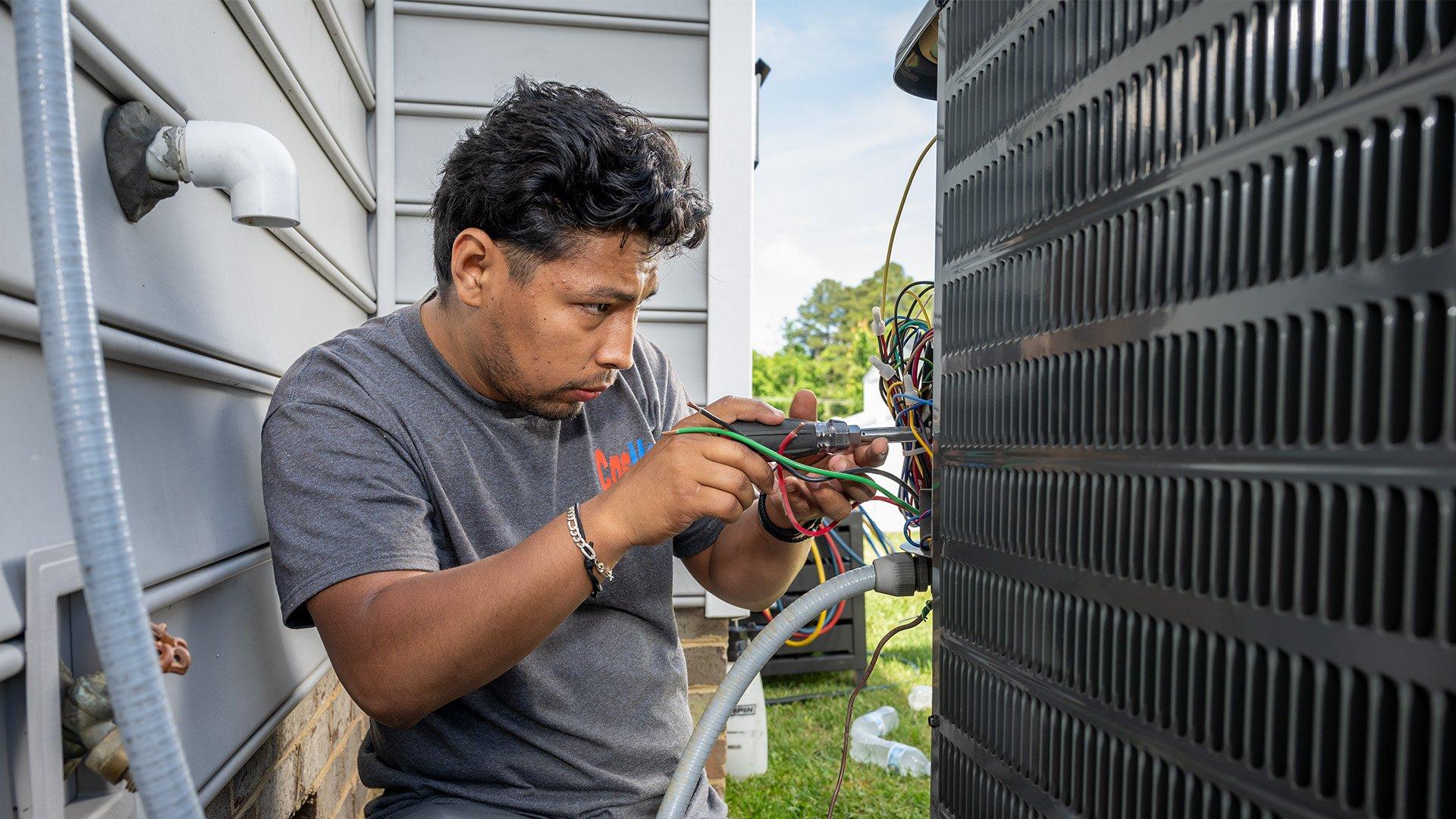 HVAC tech working on outdoor unit at residential property. 