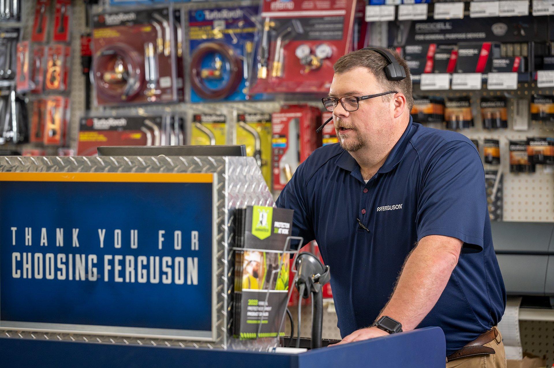 An associate wearing a headset looks at his computer behind the counter at a Ferguson location.