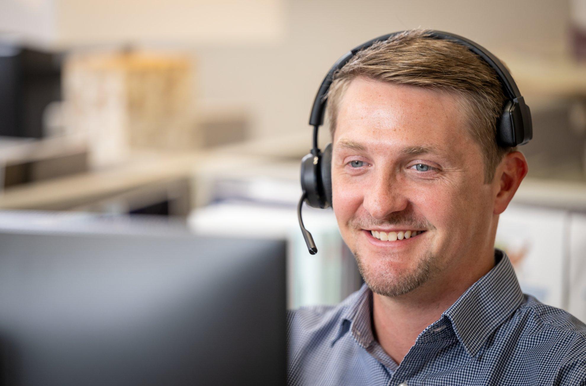 A Ferguson associate wearing a headset smiles while speaking in an office.