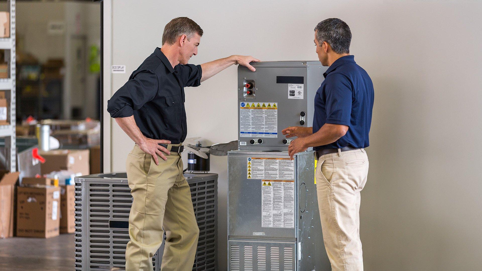 2 associates stand beside air handler and inspect. 