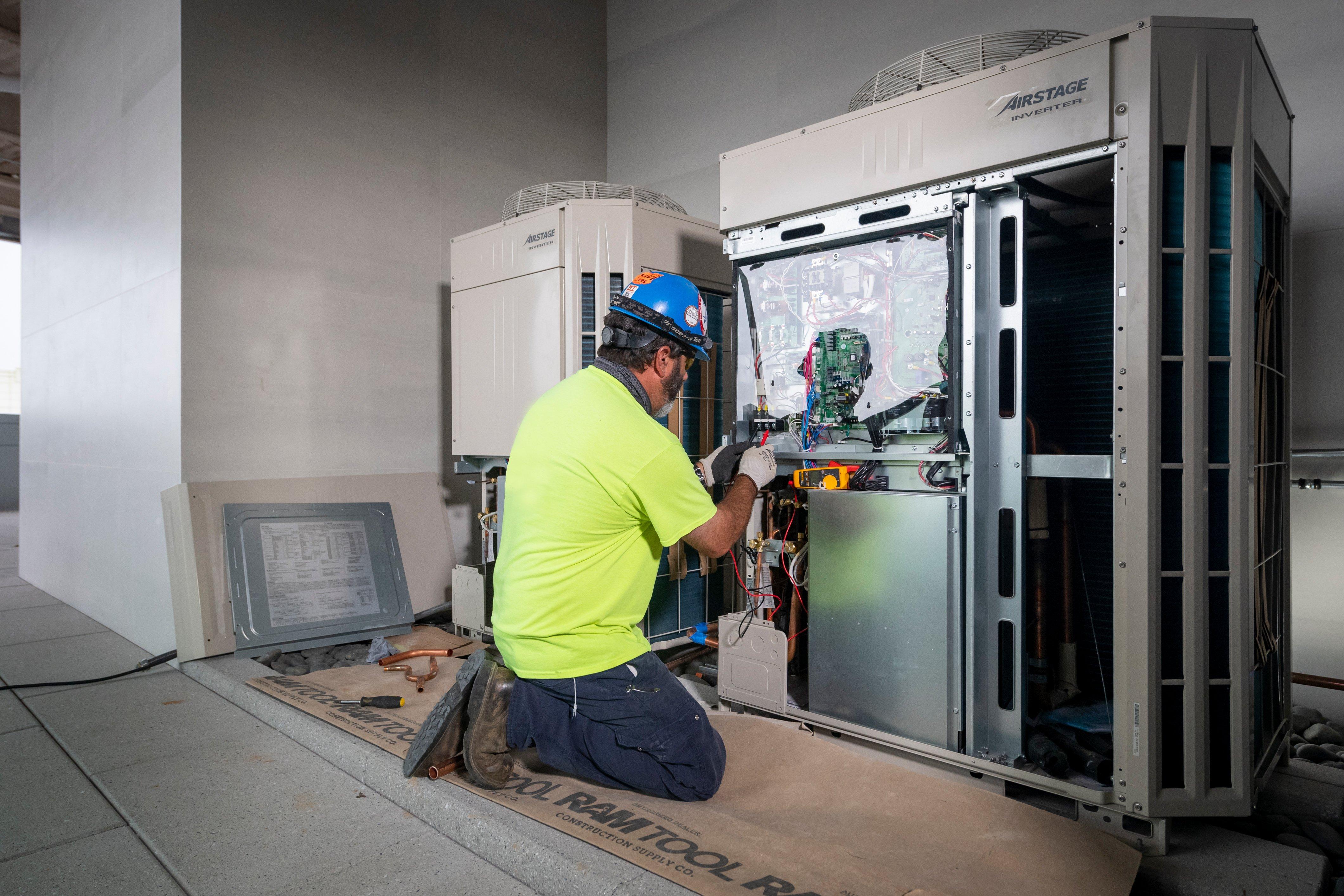 An HVAC technician works on a Fujitsu control board.