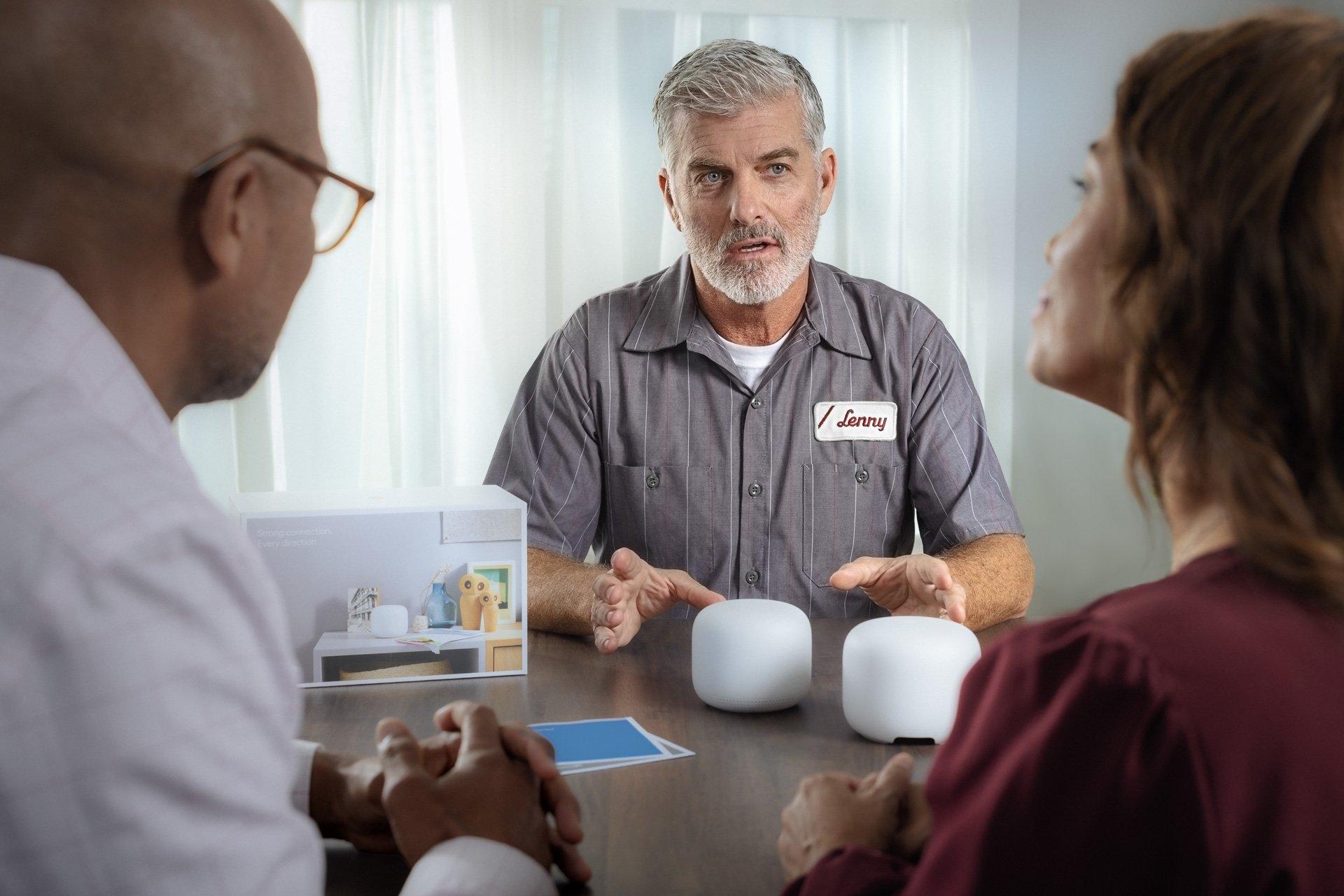 A contractor discusses Google Nest Wi-Fi routers with homeowners at a dining room table.