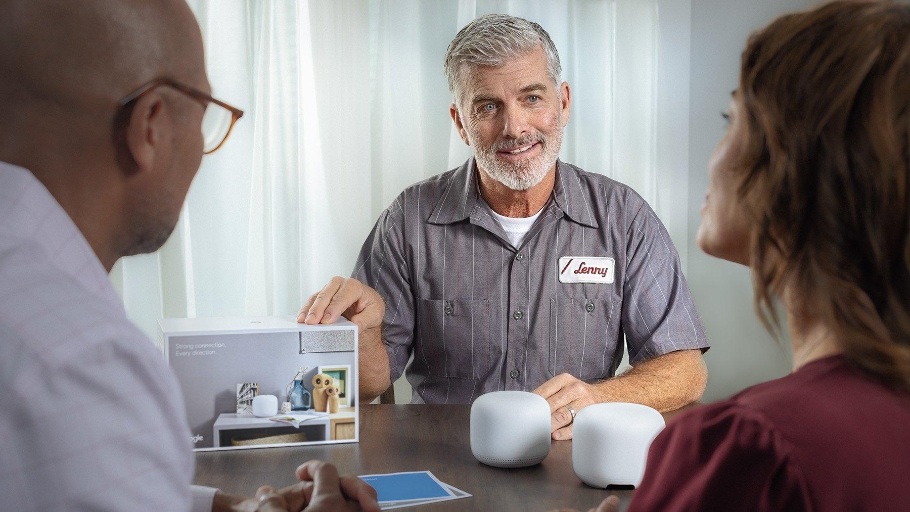 An HVAC technician discusses smart home products with homeowners at a dining room table.