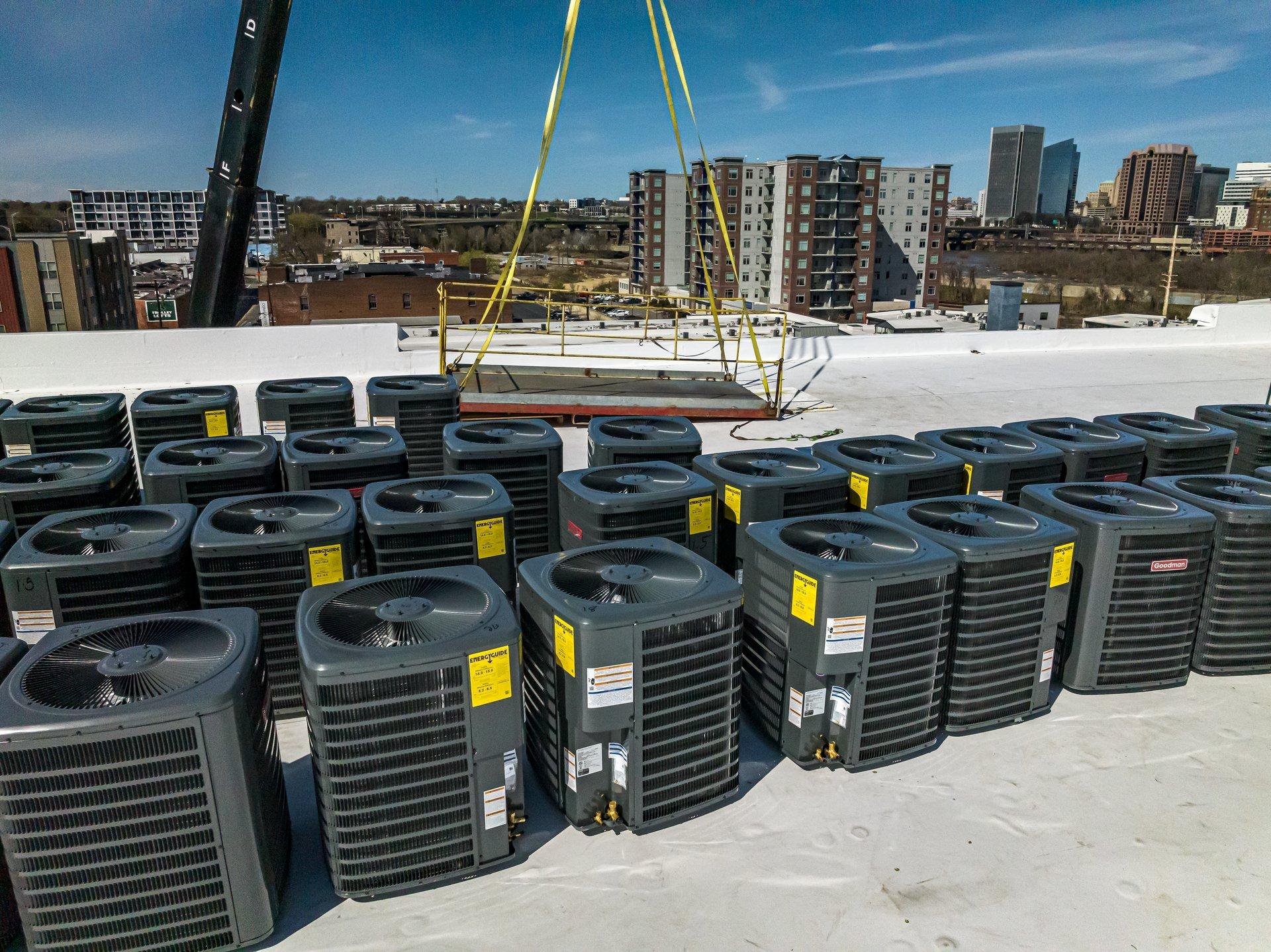 HVAC condensers are lined up on a building roof with a crane in the background.