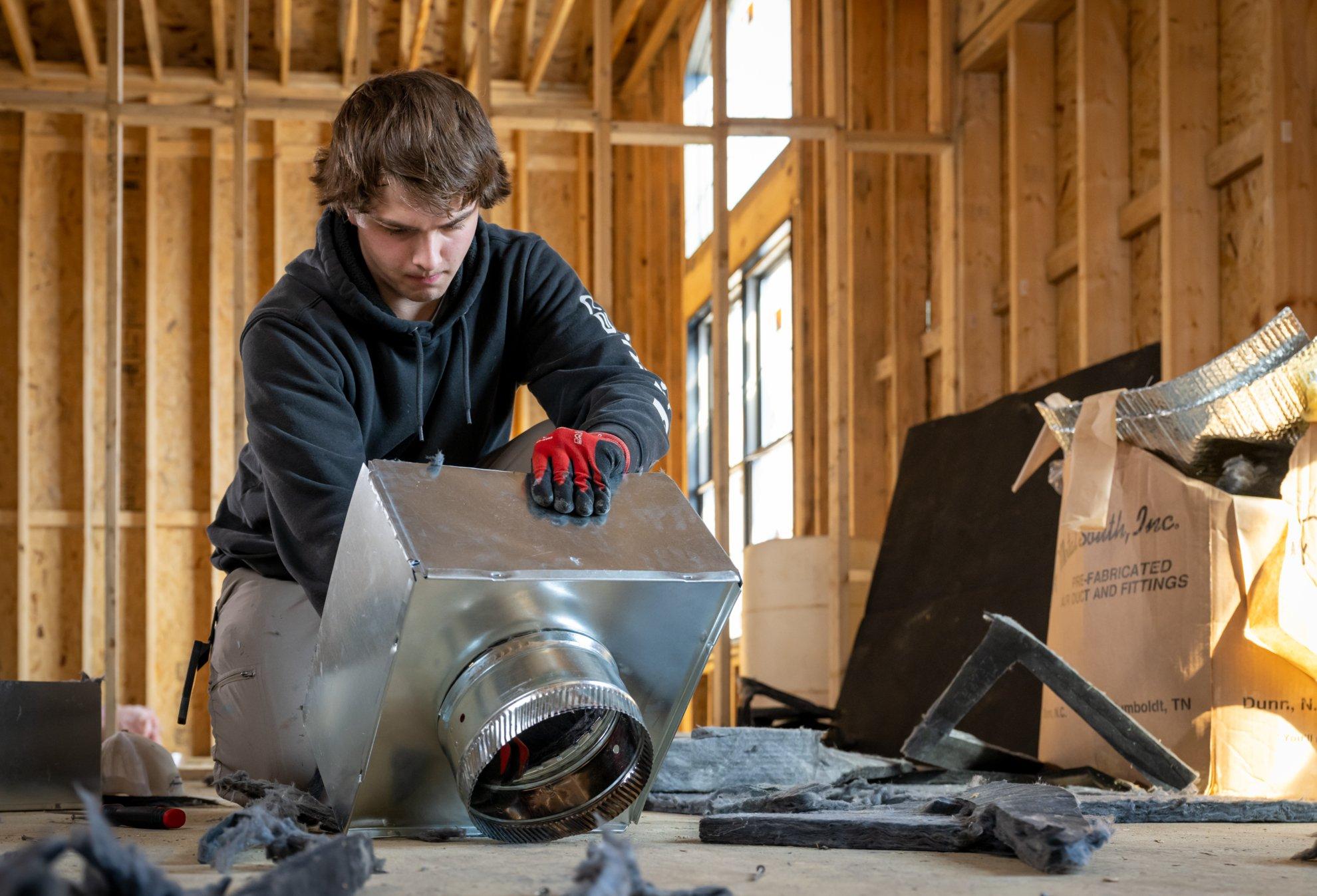 An HVAC technician inspects a distributor box in a residential new build.