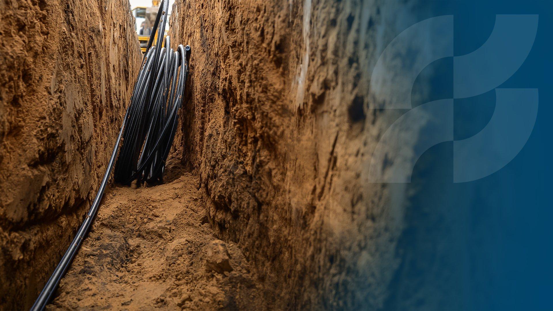 A coil of black plastic pipe leans against the wall of a narrow, deep vertical trench; to the right the Ferguson logo is laid over the image.