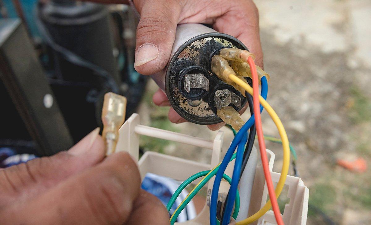 HVAC technician removes a defective capacitor from a window air conditioner