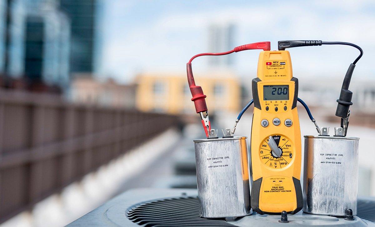 Run capacitors connected to multimeter on condenser
