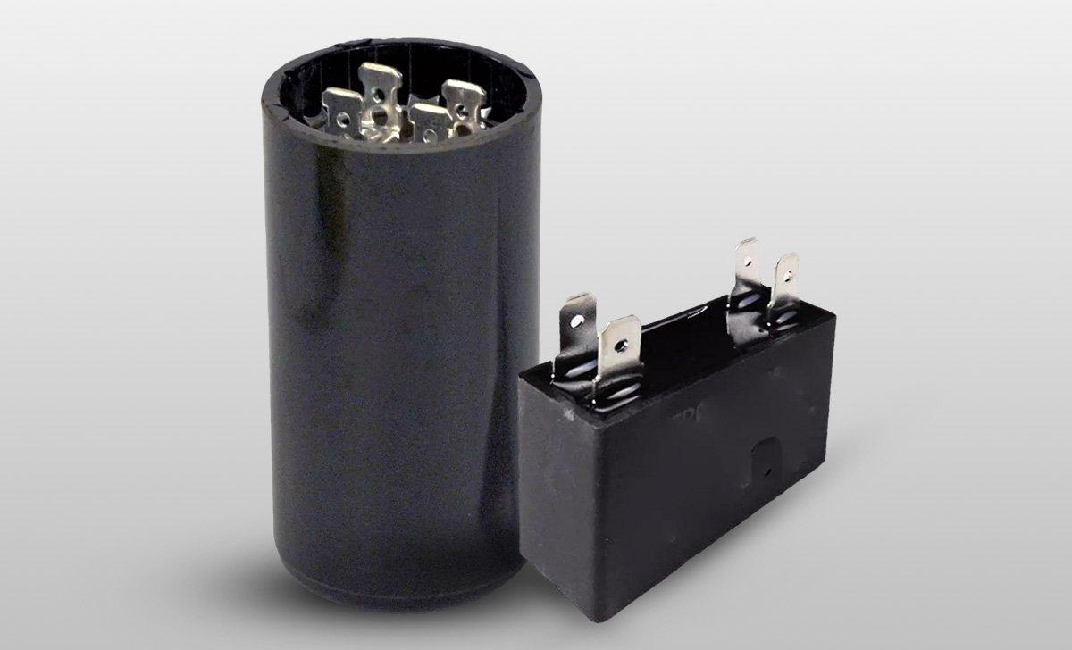 Two black plastic round and cylinder start capacitors