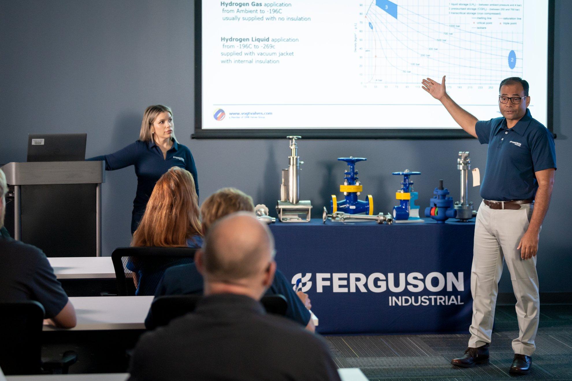 Two Ferguson Industrial associates instruct about types of pipe material for different purposes in a conference room.
