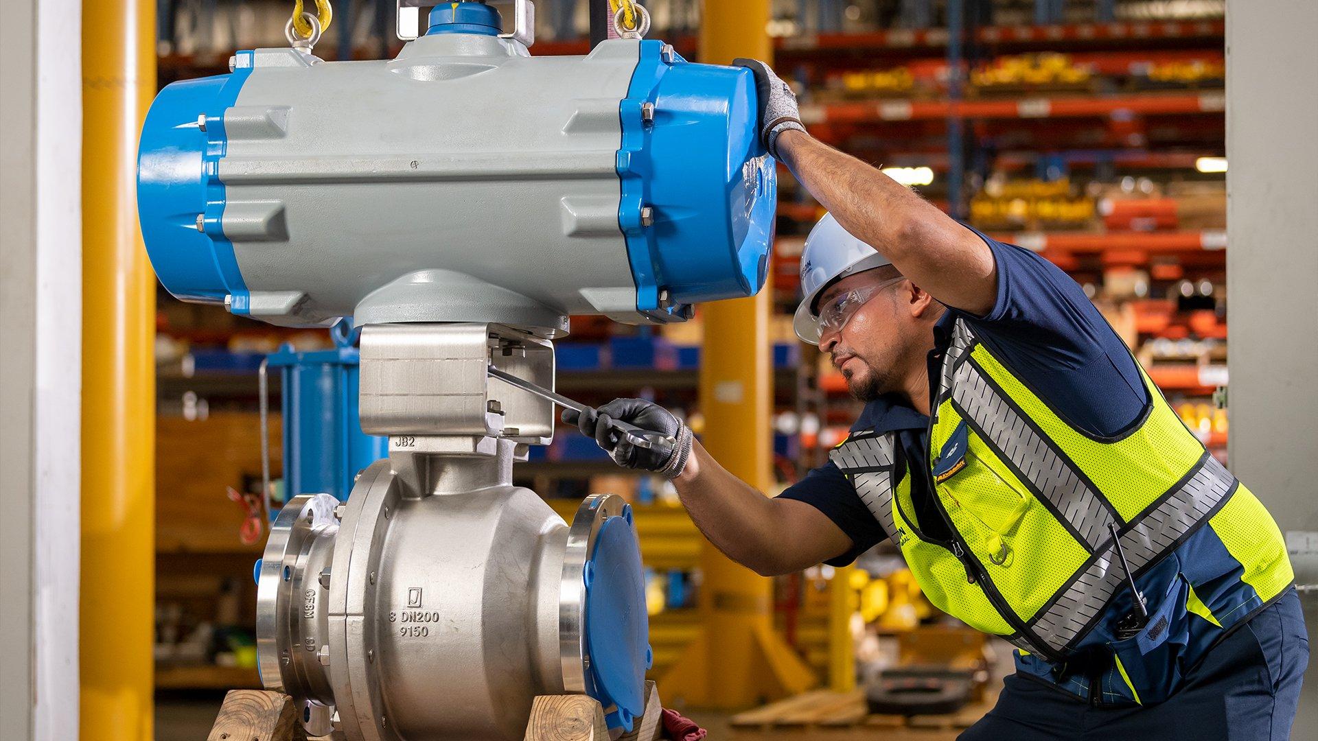 A Ferguson associate wearing protective gear uses a wrench on industrial PVF.
