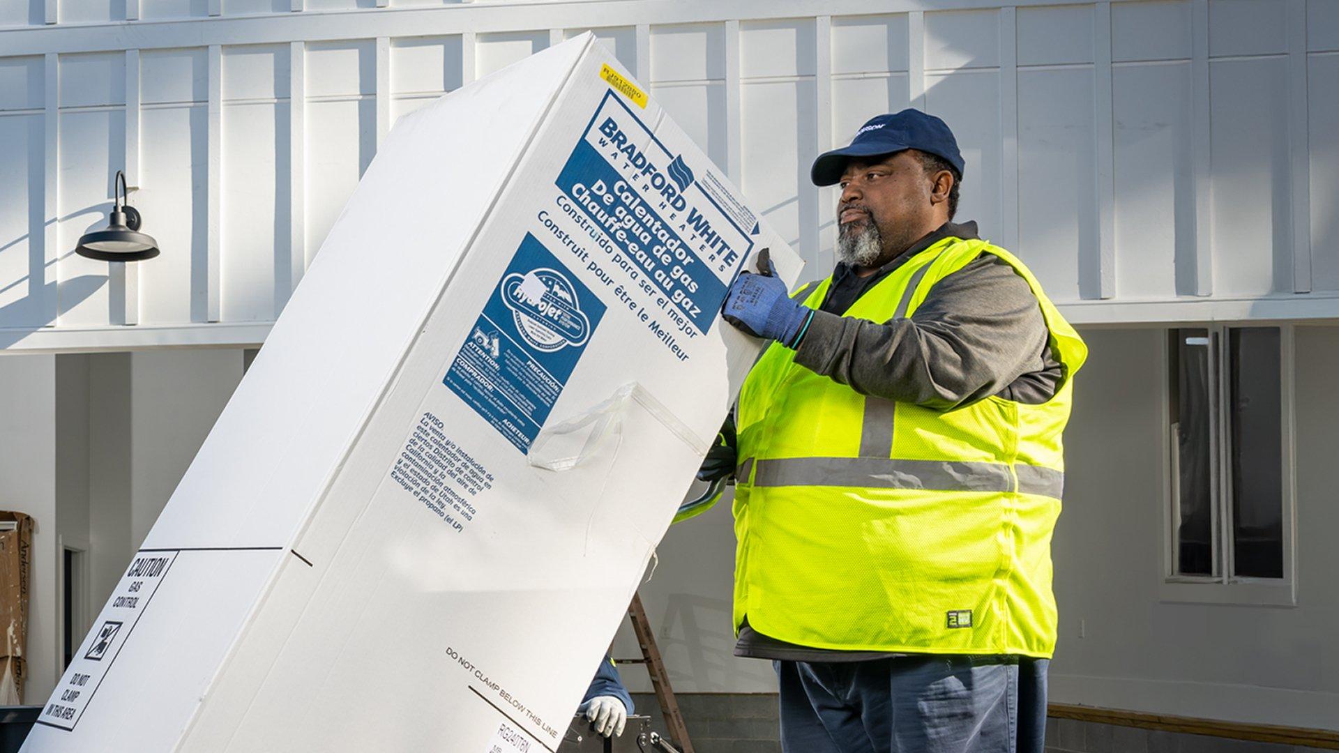 Man in safety vest loads Bradford White commercial water heaters into the bed of Ferguson truck.