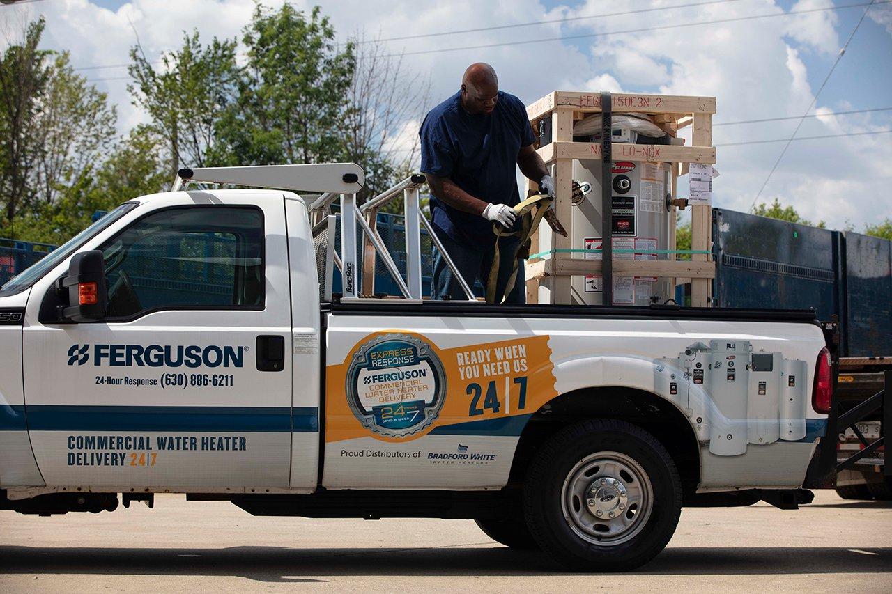 An associate stands in a Ferguson truck and unhooks a commercial water heater.