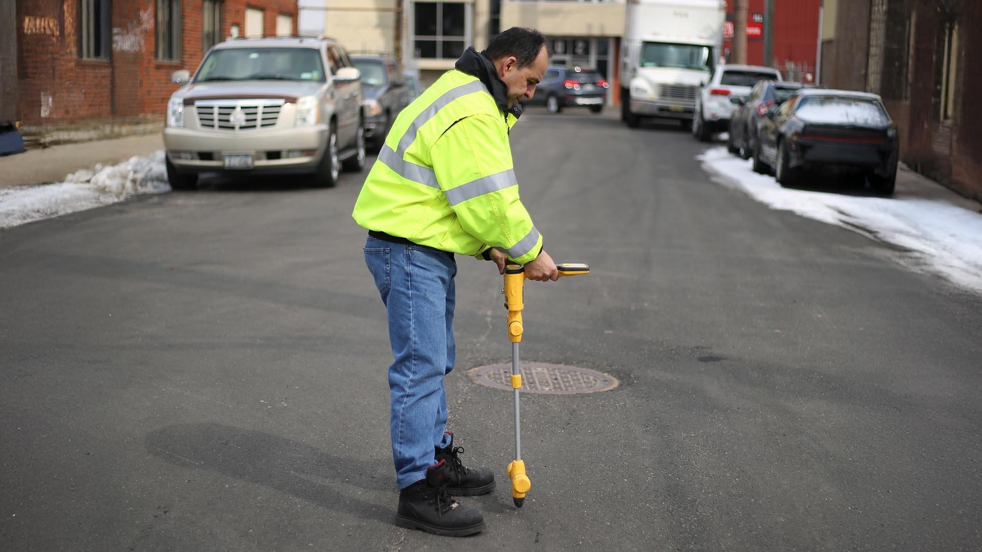 Man in safety gear uses a utility locating device