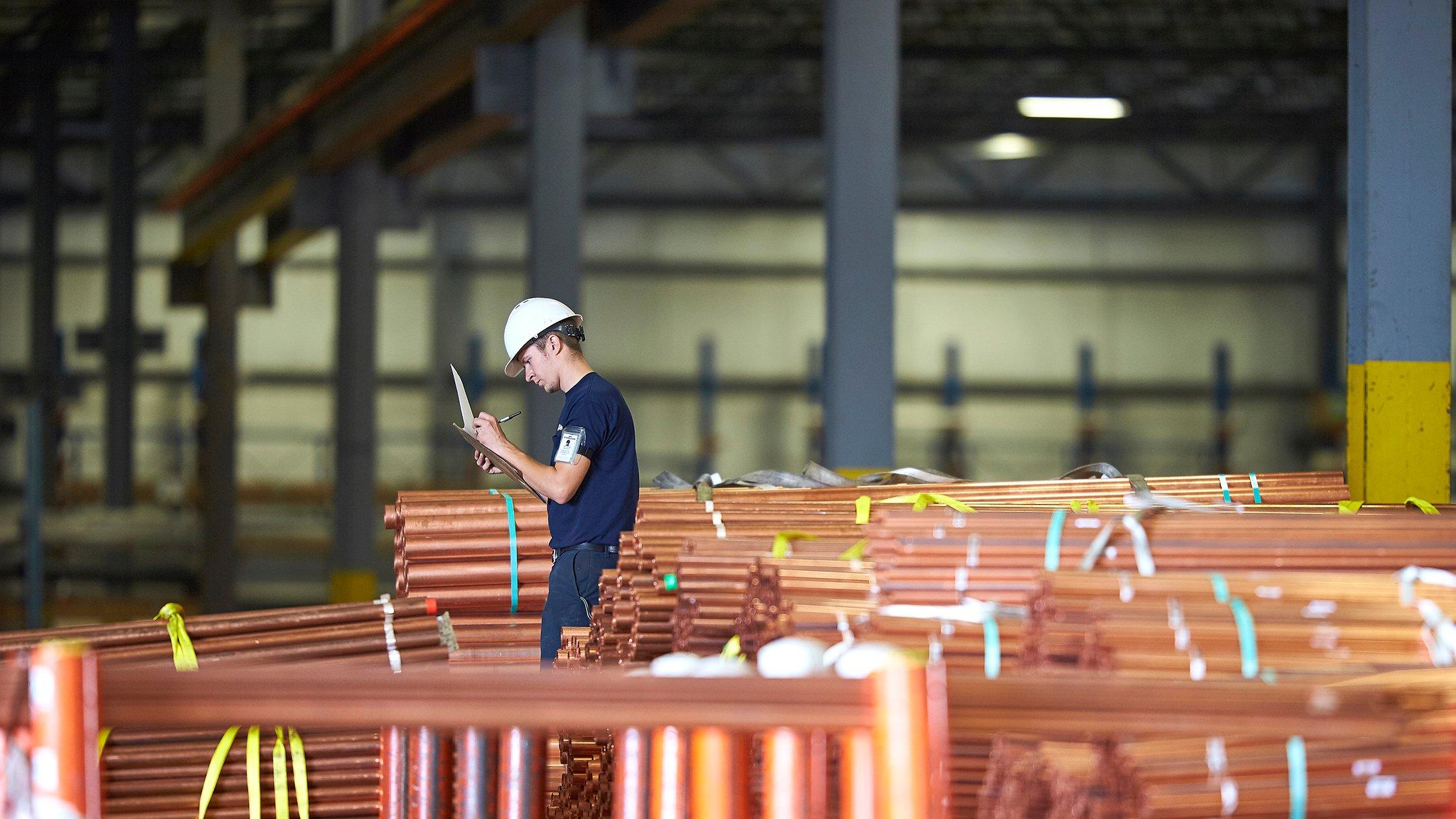 A contractor reviews stacks of pipe bundles in a commercial build.