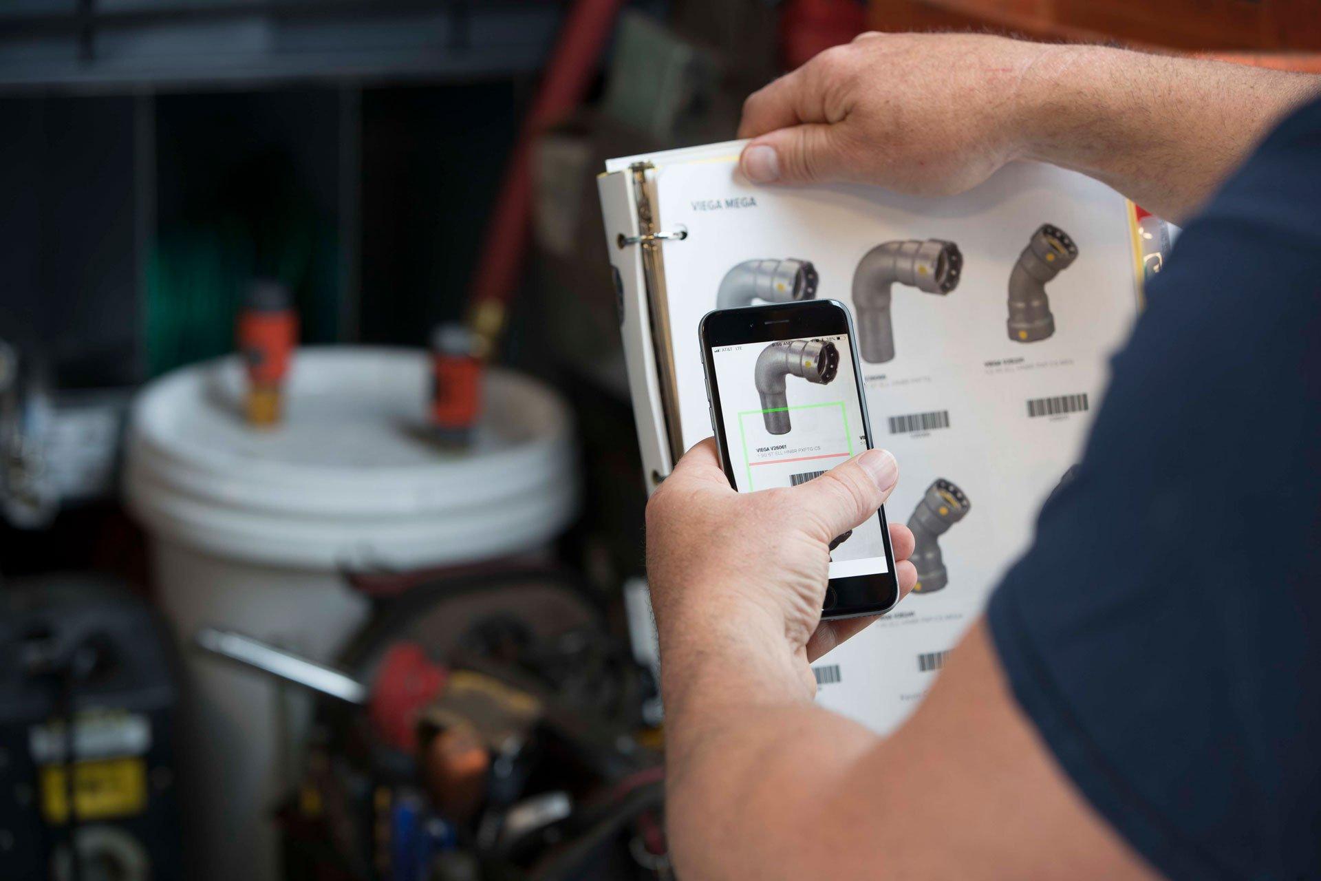 A person holds a smartphone over a scan book and scans a product barcode.