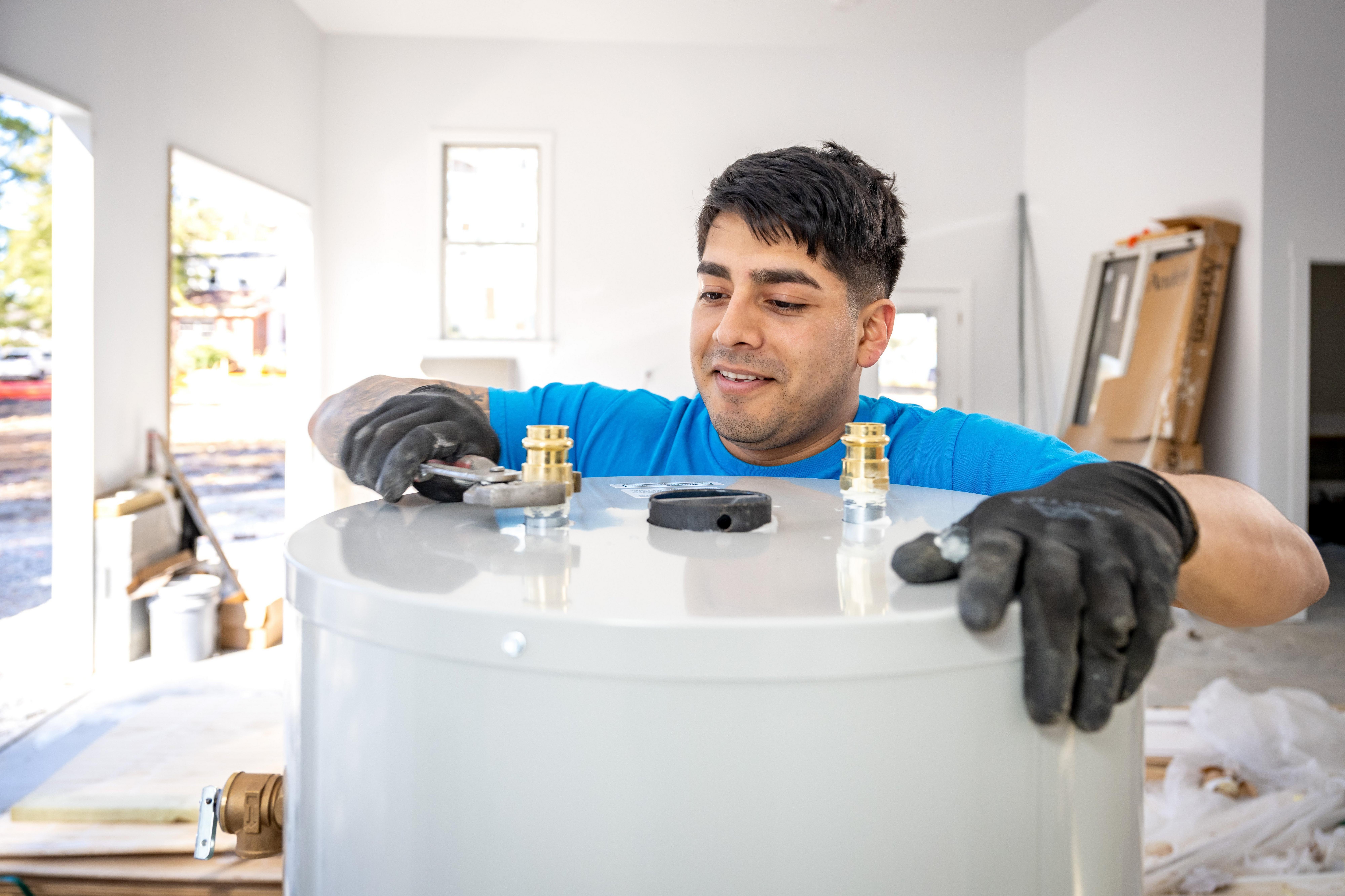A plumber installs a gas water heater in a residential garage.