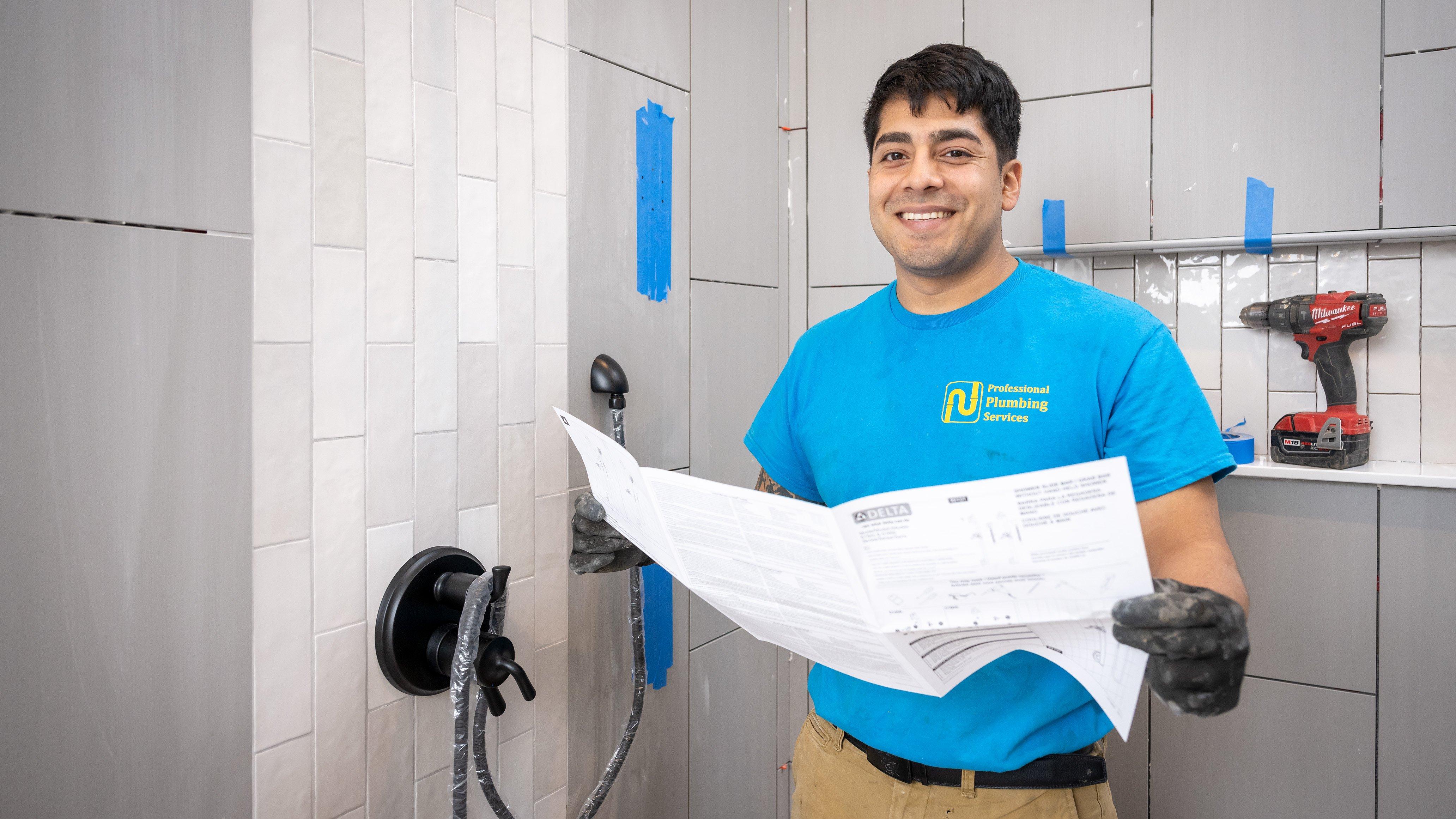 A plumber installs shower equipment in a remodeled bathroom.