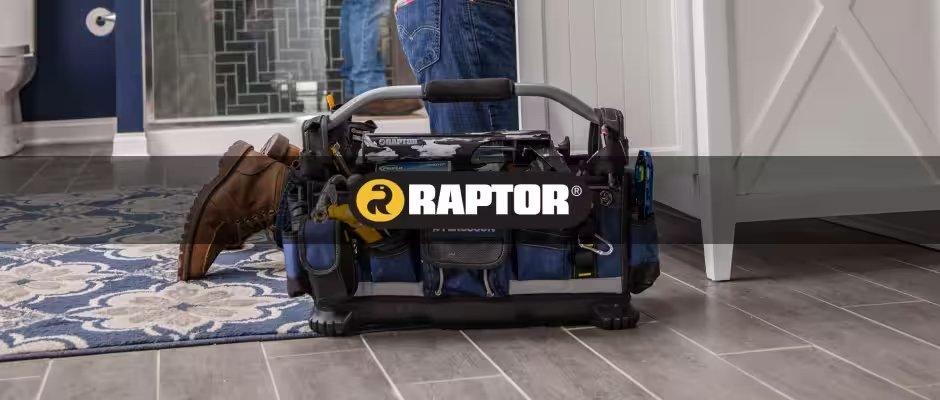 A black RAPTOR tool bag is on the floor next to a contractor kneeling under a bathroom sink.