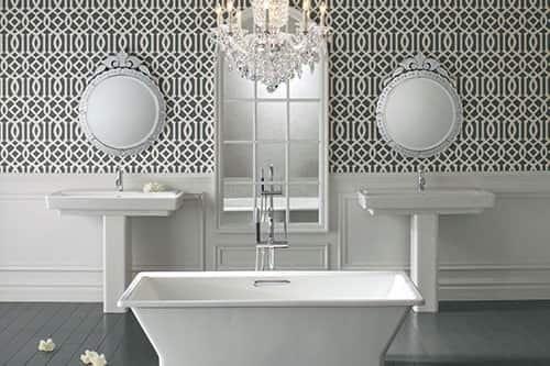 An elegant and spacious white bathroom with a standalone bath tub and double sinks, with a mirror and chandelier.