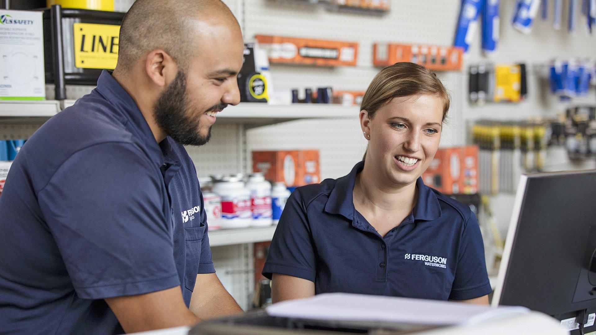 Two Ferguson associates inside a branch look over computer together. 