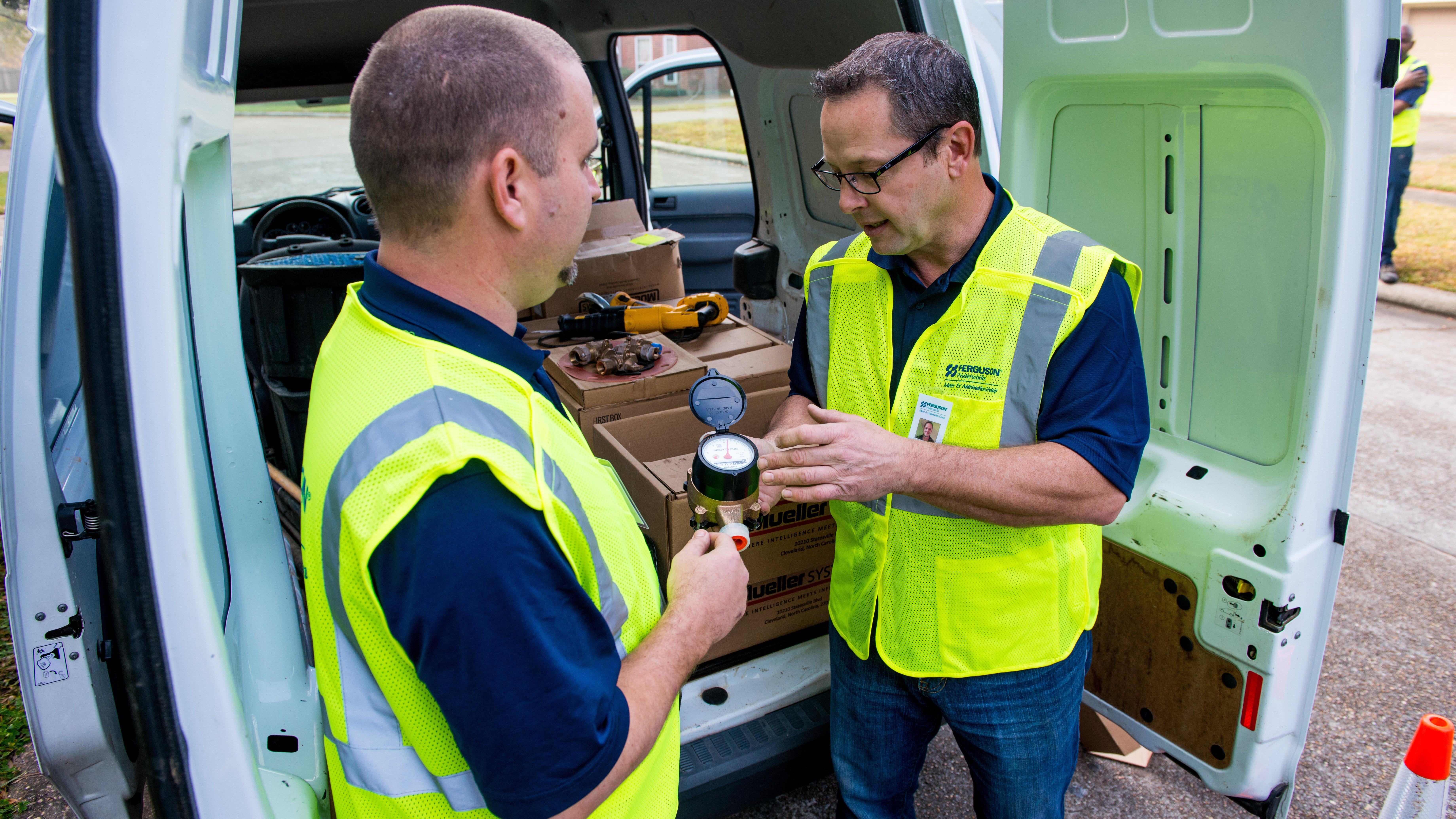 Two Ferguson associates discuss a water meter outside of a work van.