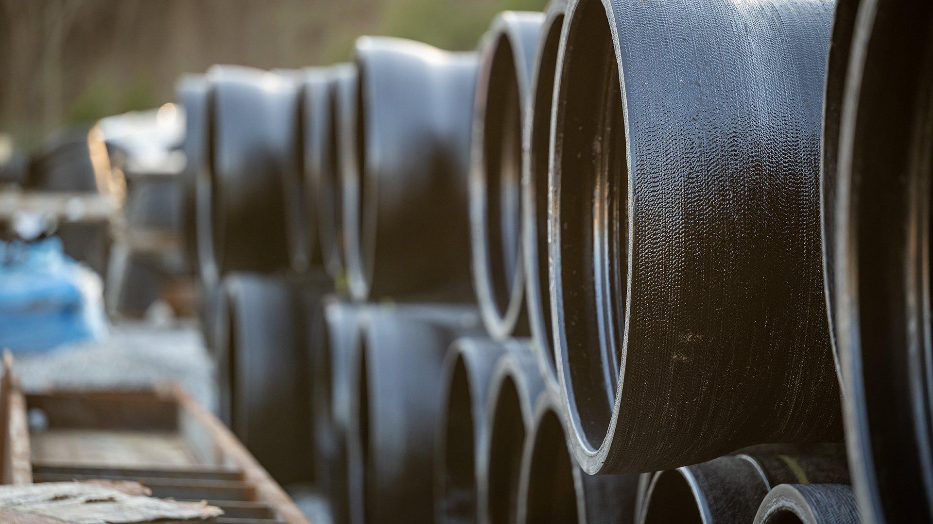 View of black water pipe stacked with open ends facing left.