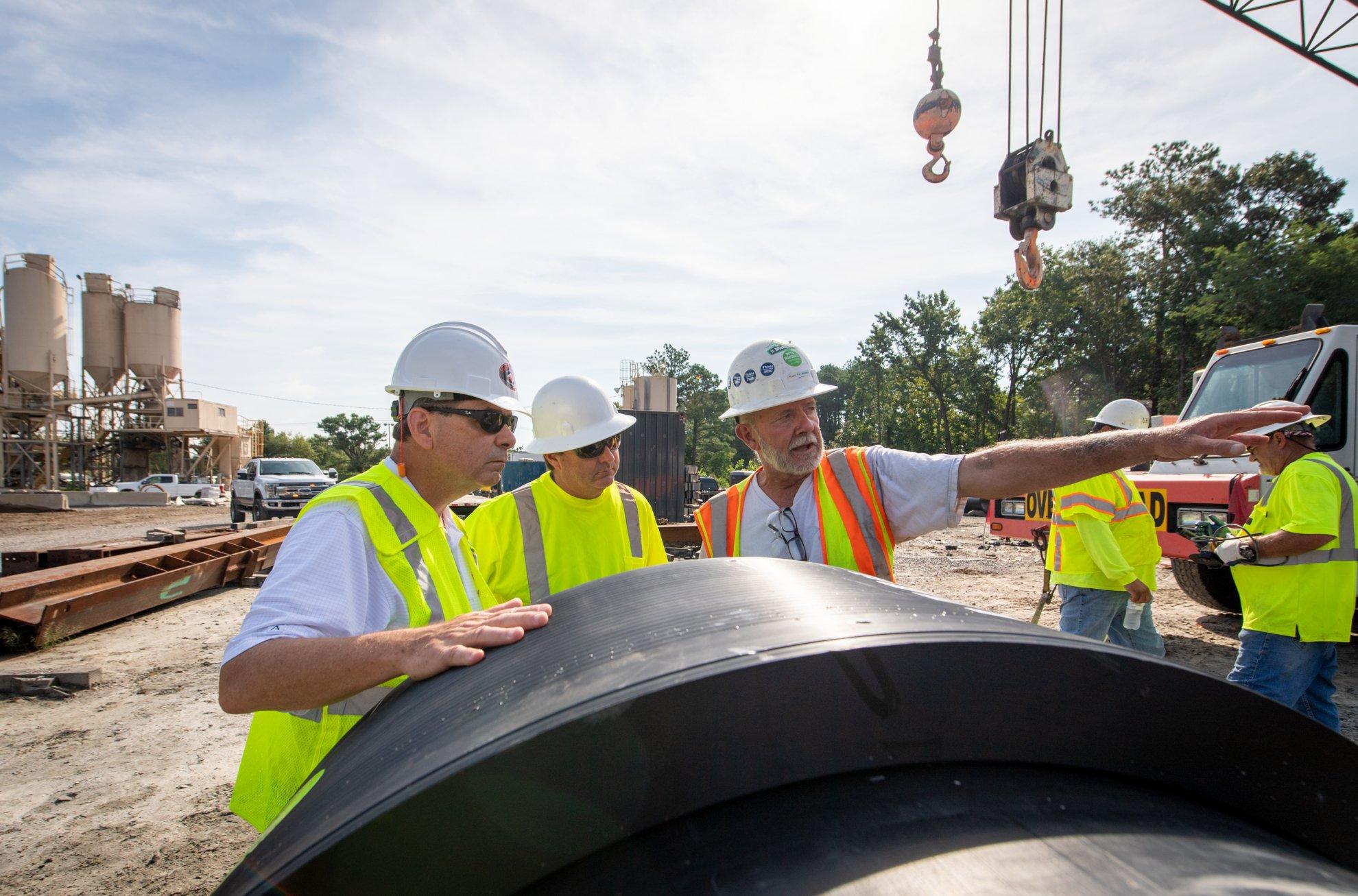 Workers on a construction jobsite wear hardhats and reflective gear.