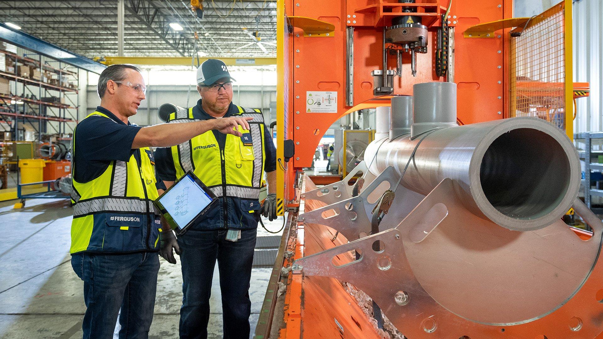 Two workers discuss fabrication in commercial building. 
