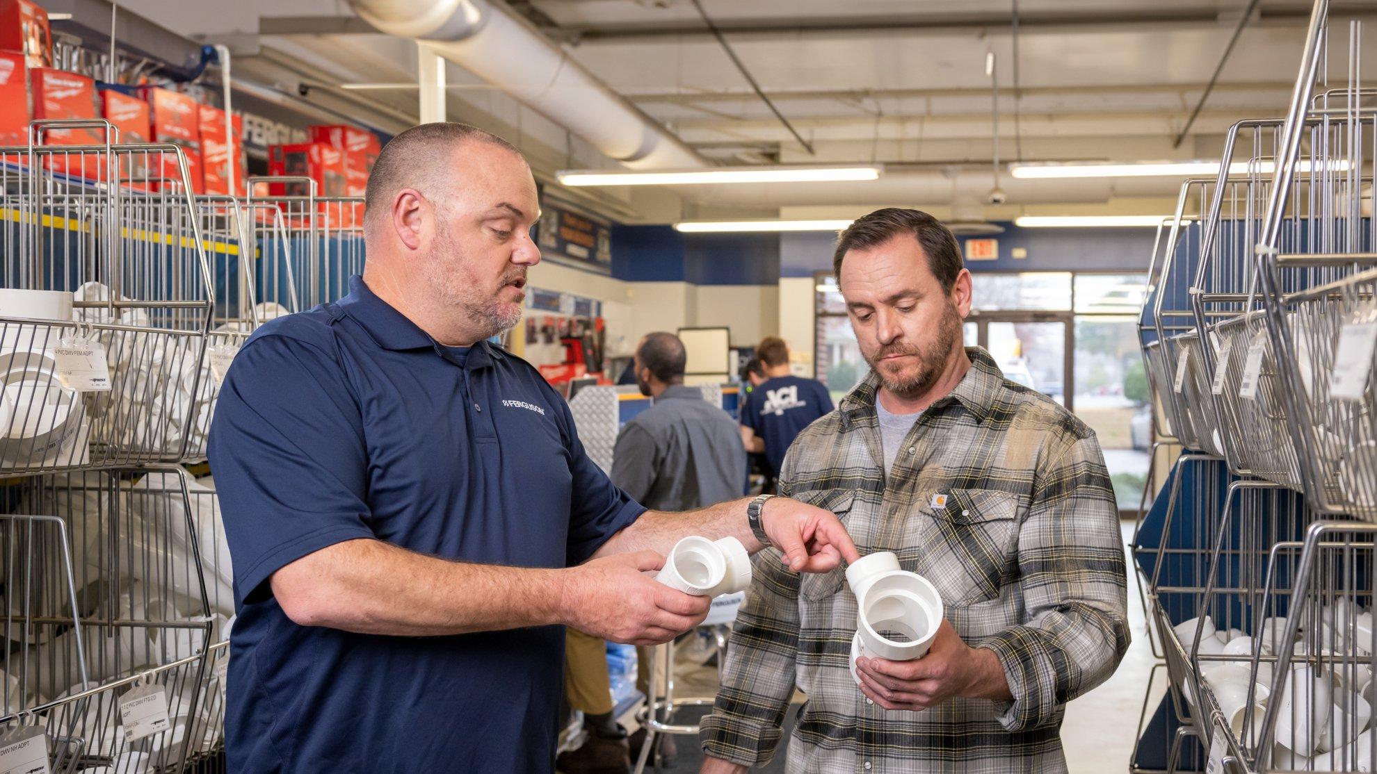 A Ferguson associate discusses pipe fittings with a customer at a counter location.