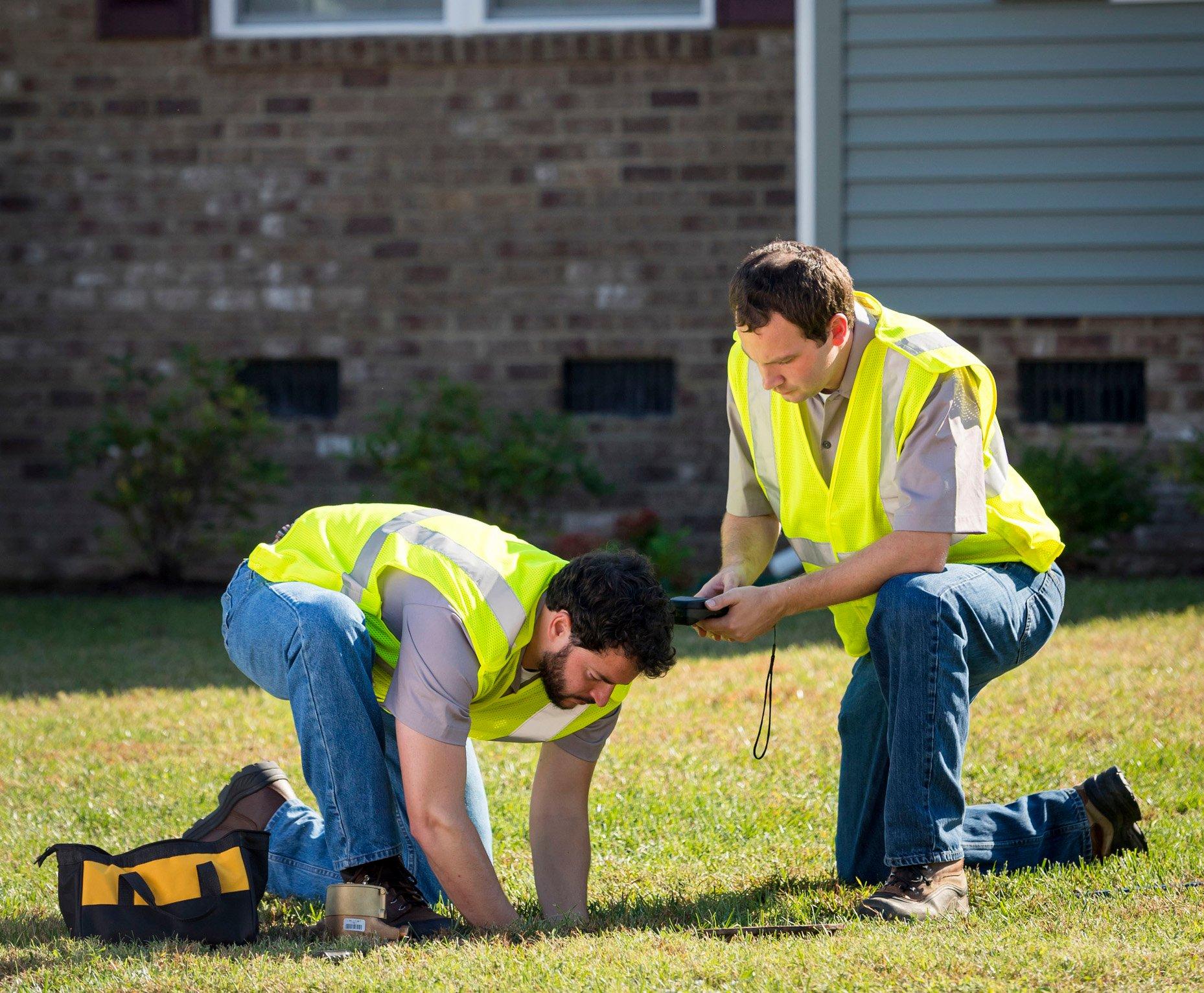 Two Ferguson associates install a water meter underground in a home’s yard.
